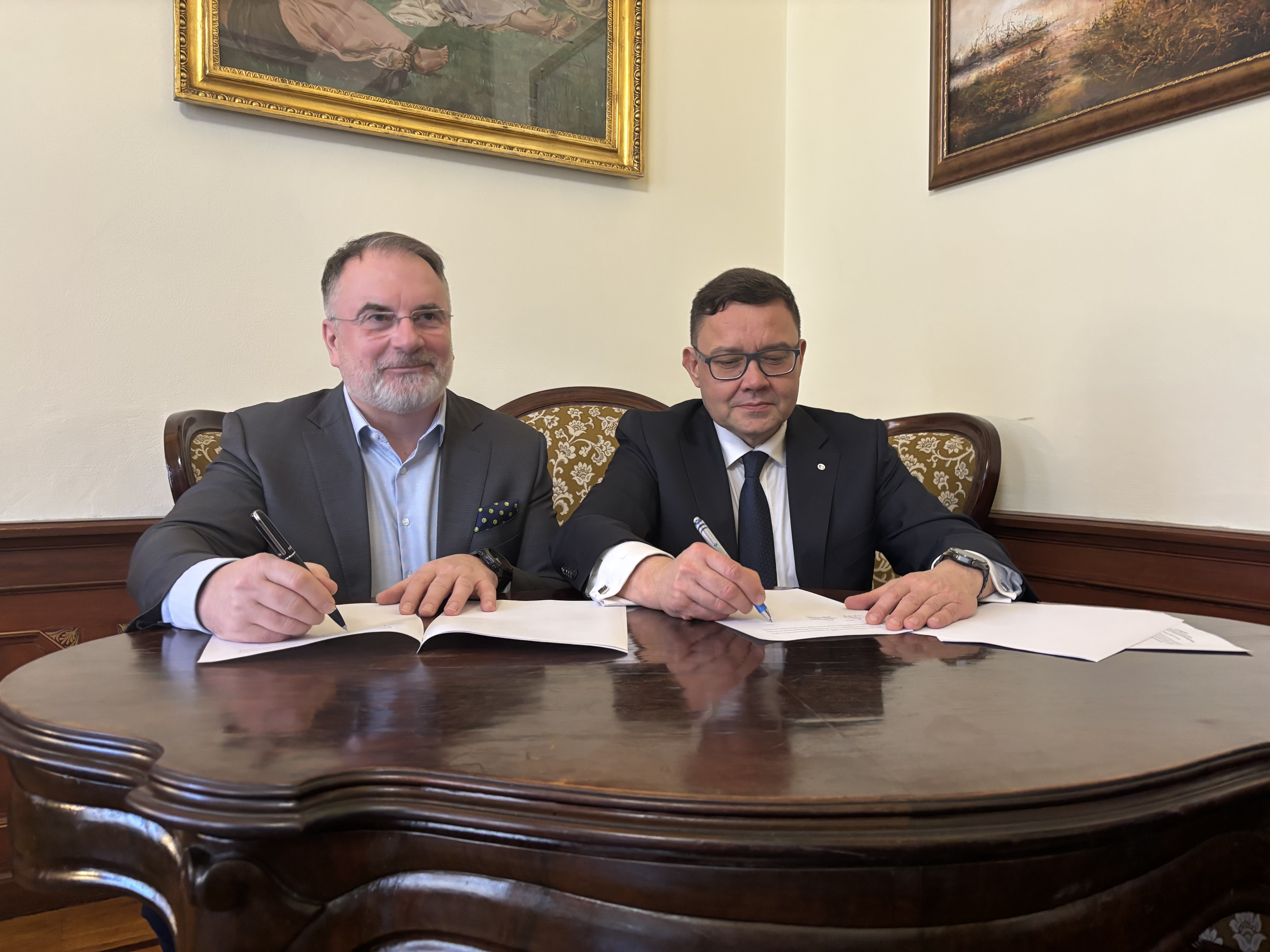 Wojciech Pomajda (Członek Zarządu KGS S.A.) oraz dr inż. Tomasz Jacek (Dyrektor Instytutu Zootechniki PIB) podpisują porozumienie siedząc przy stole